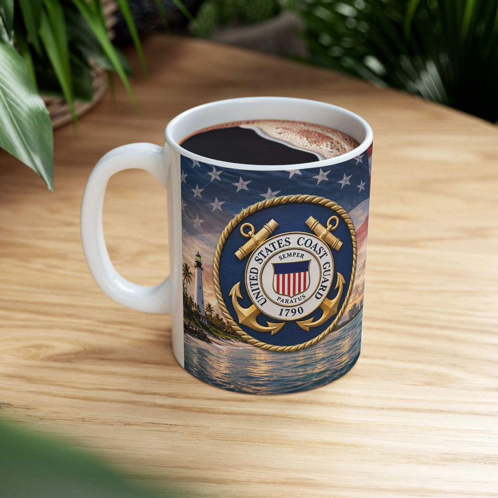 A mug with a design featuring the United States Coast Guard seal and a nautical scene, including a lighthouse and a ship, on a wooden surface.
