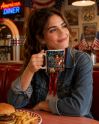 A woman is sitting at a table in a diner, holding a mug with a design that says "250th of June 1966". She is smiling and looking up, with a burger and fries on the table in front of her.
