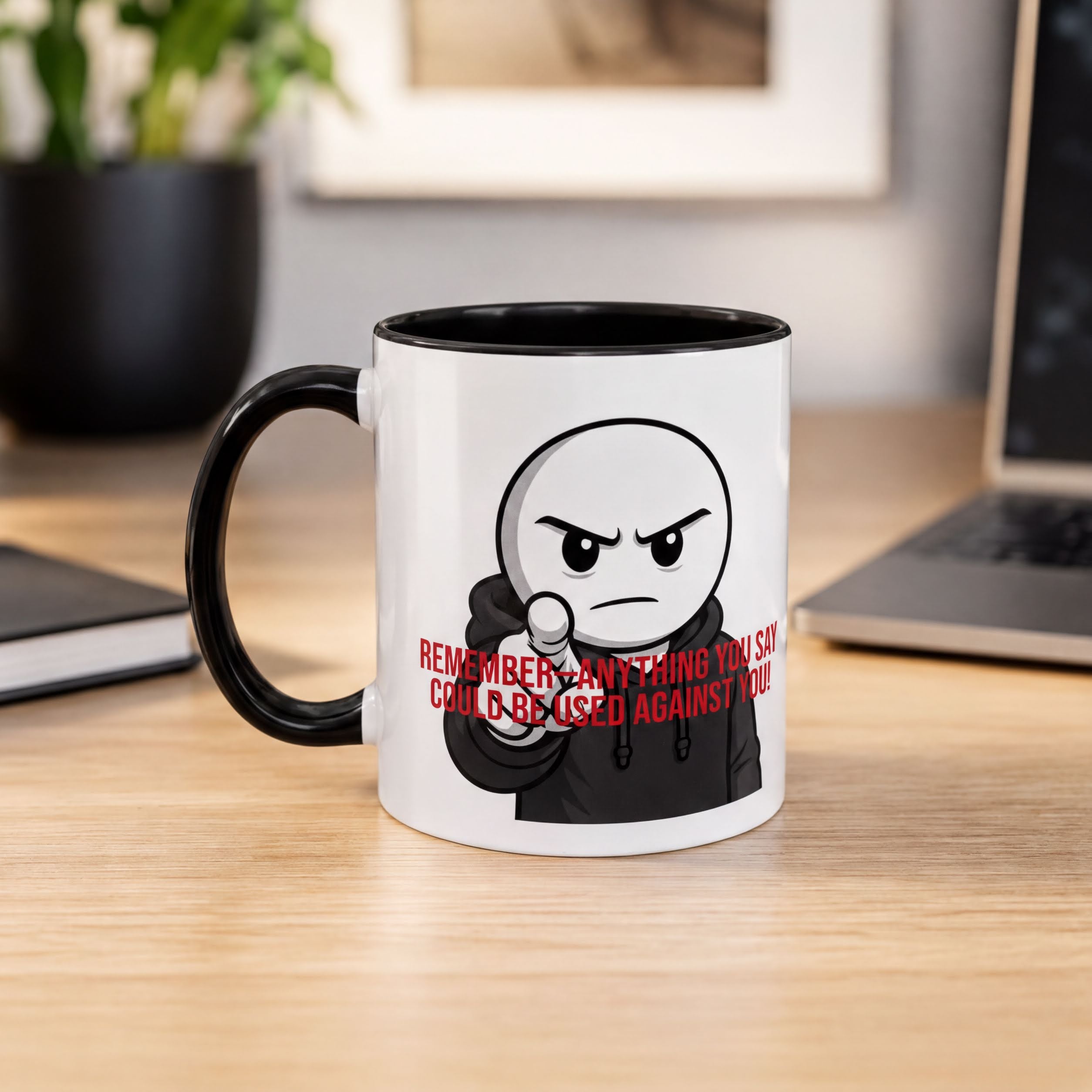 A white mug with a cartoon character and text printed on it, placed on a wooden desk.