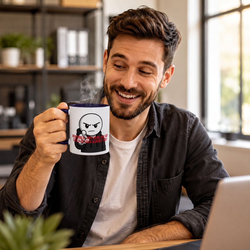 A man is sitting at a desk, smiling and holding a mug with a cartoon character on it.