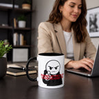 A woman is sitting at a desk, working on a laptop computer. She is wearing a beige jacket and has a mug with a cartoon character on it in front of her.