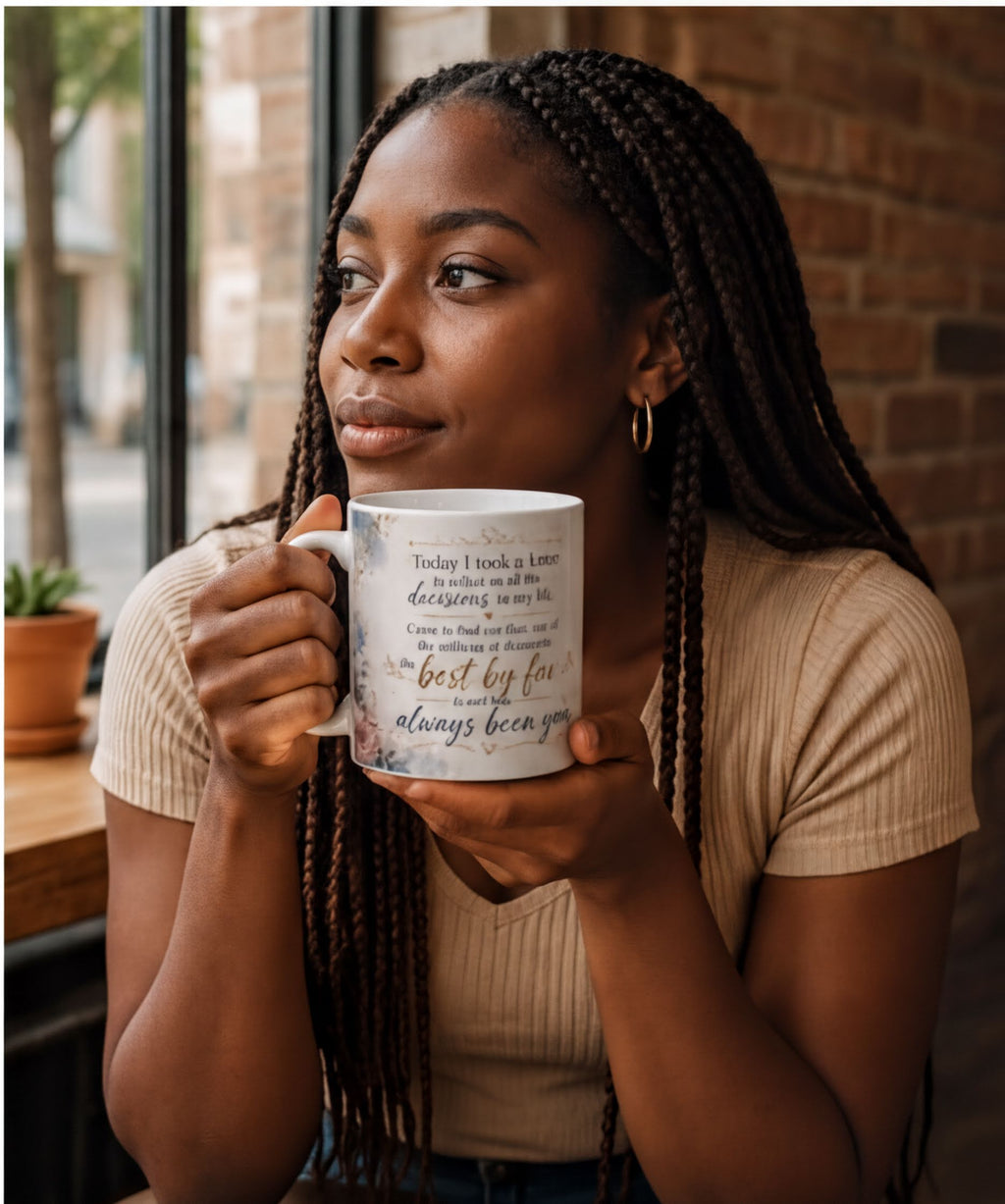 A woman with braided hair is holding a mug with text on it, looking to the side with a thoughtful expression.