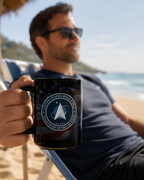 A man is sitting on a beach chair, holding a black mug with an American flag design and the text "United States Space Force" printed on it.