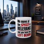 A white mug with text on it, placed on a desk in an office setting with a cityscape visible through a window.