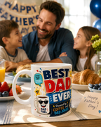A man and two children are sitting at a table with a white mug featuring a humorous design, surrounded by food and drinks.