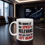 A white coffee mug with text printed on it, placed on a wooden table in an office setting.