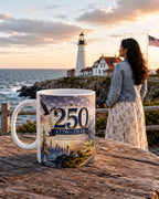 A woman stands near a lighthouse, overlooking the ocean, with a mug featuring a design of the Statue of Liberty and the text "250 1776-2026 United States of America" in the foreground.