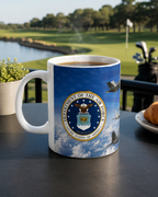 A mug with the United States Air Force seal on it, placed on a table with a golf club and a plate of food in the background.